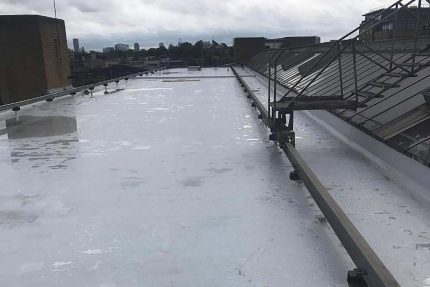 Completed flat roof upgrade featuring new safety railings for secure maintenance access.