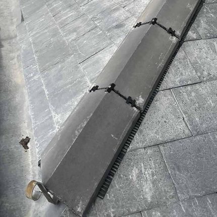 Detailed view of an advanced dry fix ridge system and architectural lead valley completed on a commercial structure by our North London roofing specialists.