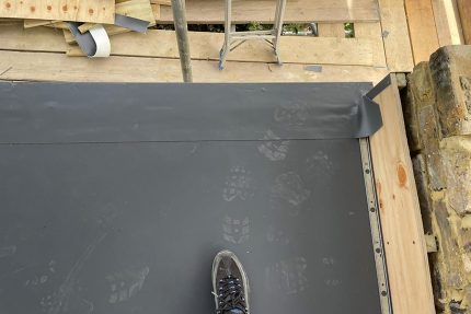 Professional roofing contractors preparing the surface for a new Sika Sarnafil single-ply flat roof installation.