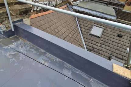 Professional roofers replacing an old, leaking flat roof with an energy-efficient warm roof system.
