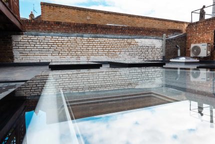 A completed flat roof project in Chelsea showing integrated Velux windows and traditional ridge tiles.
